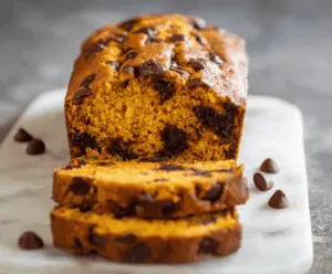 Delicious homemade pumpkin chocolate chip bread sliced with visible chocolate chips and pumpkin puree, perfect for fall desserts and breakfast