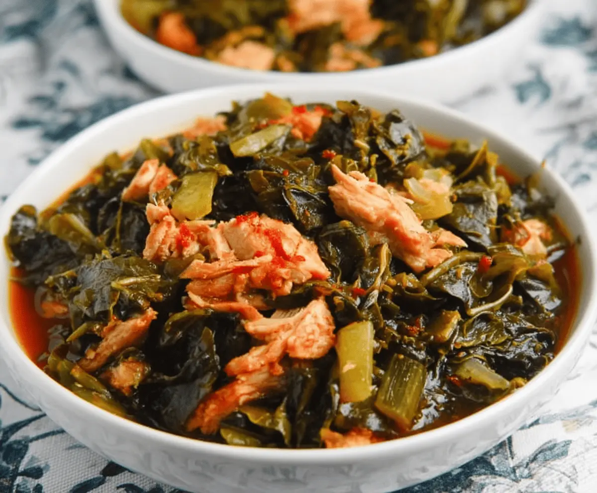 Plate of savory collard greens cooked with tender smoked turkey, garnished with fresh herbs.