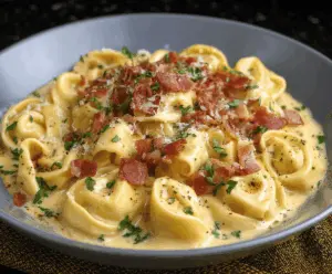 Creamy tortellini carbonara topped with grated Parmesan cheese and crispy pancetta, served on a white plate.