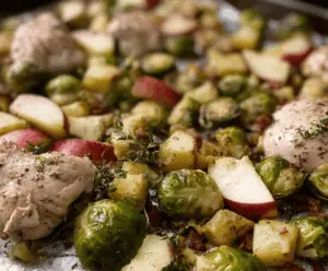 Roasted chicken, crisp apple slices, and Brussels sprouts on a sheet pan perfect for a healthy dinner.