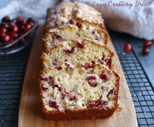 Delicious Eggnog Cranberry Bread topped with fresh cranberries and a dusting of powdered sugar.