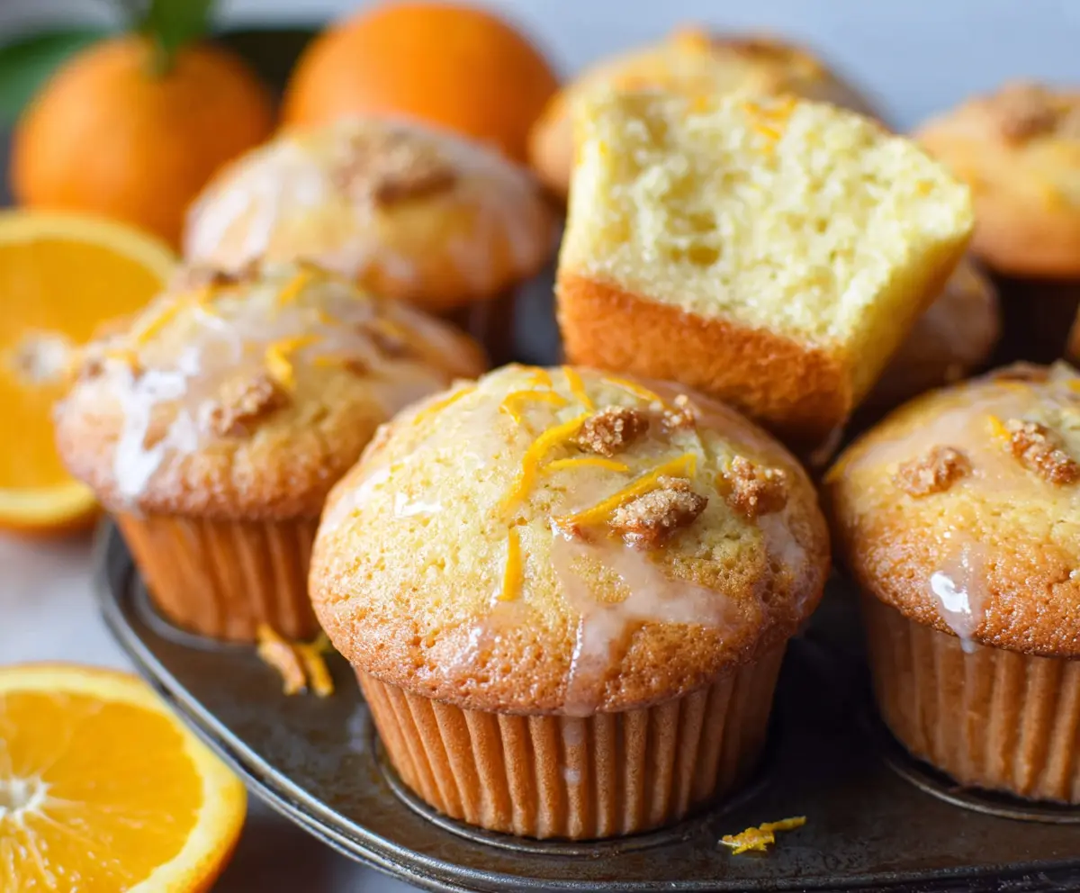 Freshly baked orange muffins with a bright orange glaze on a white plate