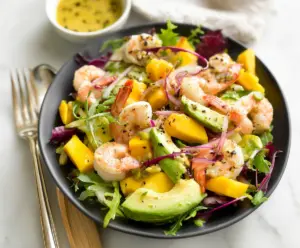 Fresh shrimp and ripe mango salad with colorful vegetables on a white plate
