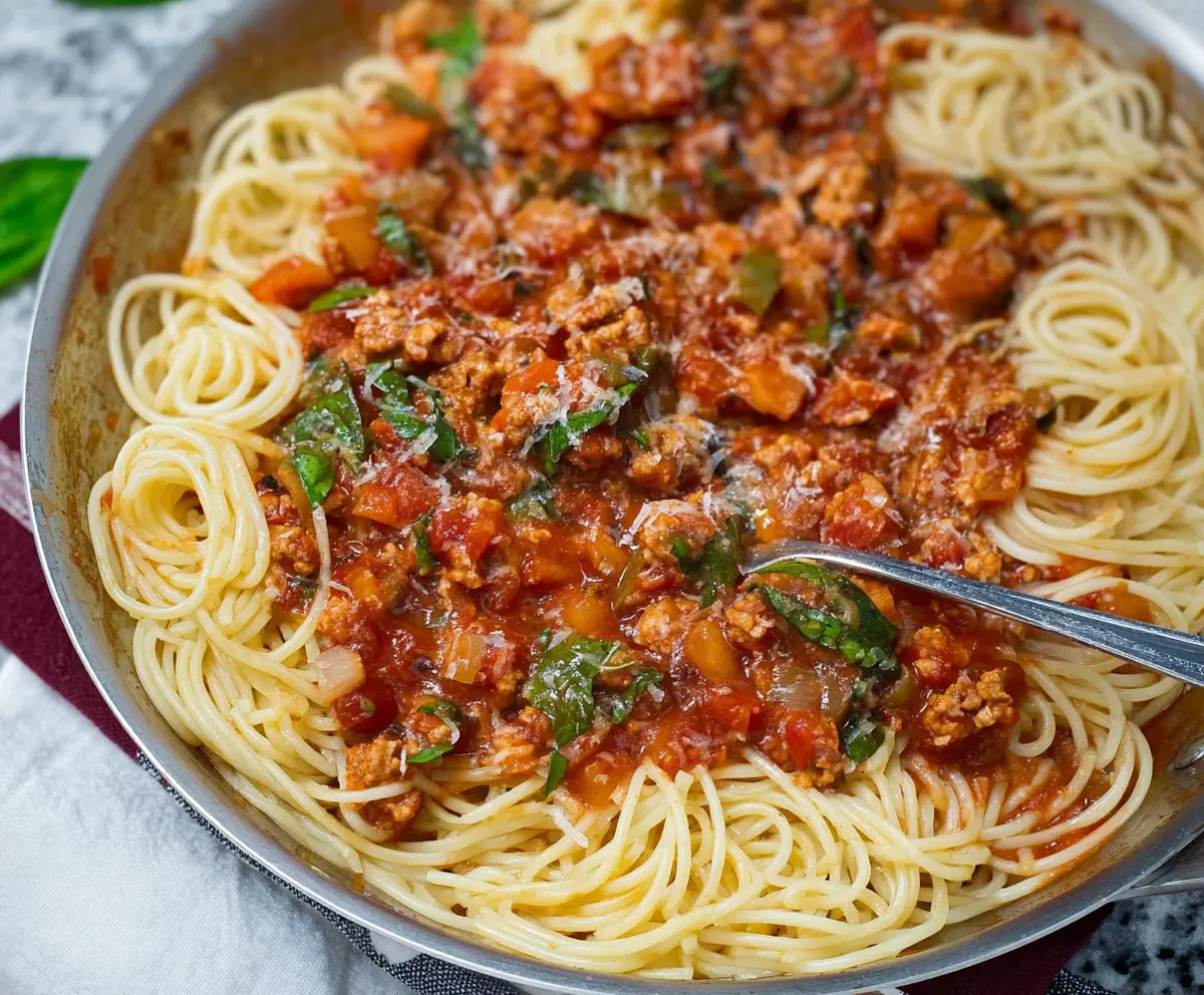 Delicious veggie-loaded ground chicken spaghetti sauce in a bowl with fresh vegetables.