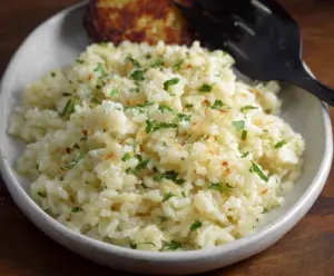Delicious garlic Parmesan rice served in a bowl, garnished with fresh herbs.