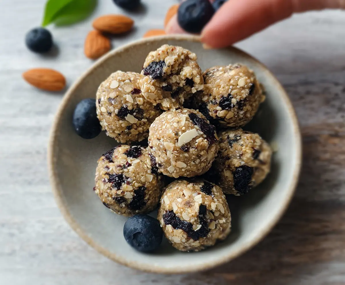 Healthy Blueberry Almond Energy Bites on a white plate, garnished with fresh blueberries and sliced almonds for a nutritious snack.
