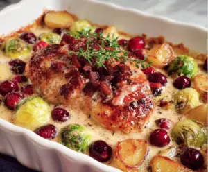 Creamy cranberry chicken served with fresh herbs on a white plate, perfect for a cozy dinner.