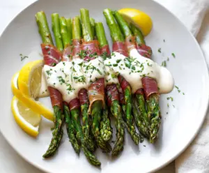 Delicious prosciutto-wrapped asparagus topped with lemon cream sauce, perfect for appetizers.