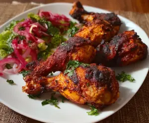 Juicy Tandoori Chicken drumsticks served with vibrant spices and herbs, perfect for a flavorful meal.